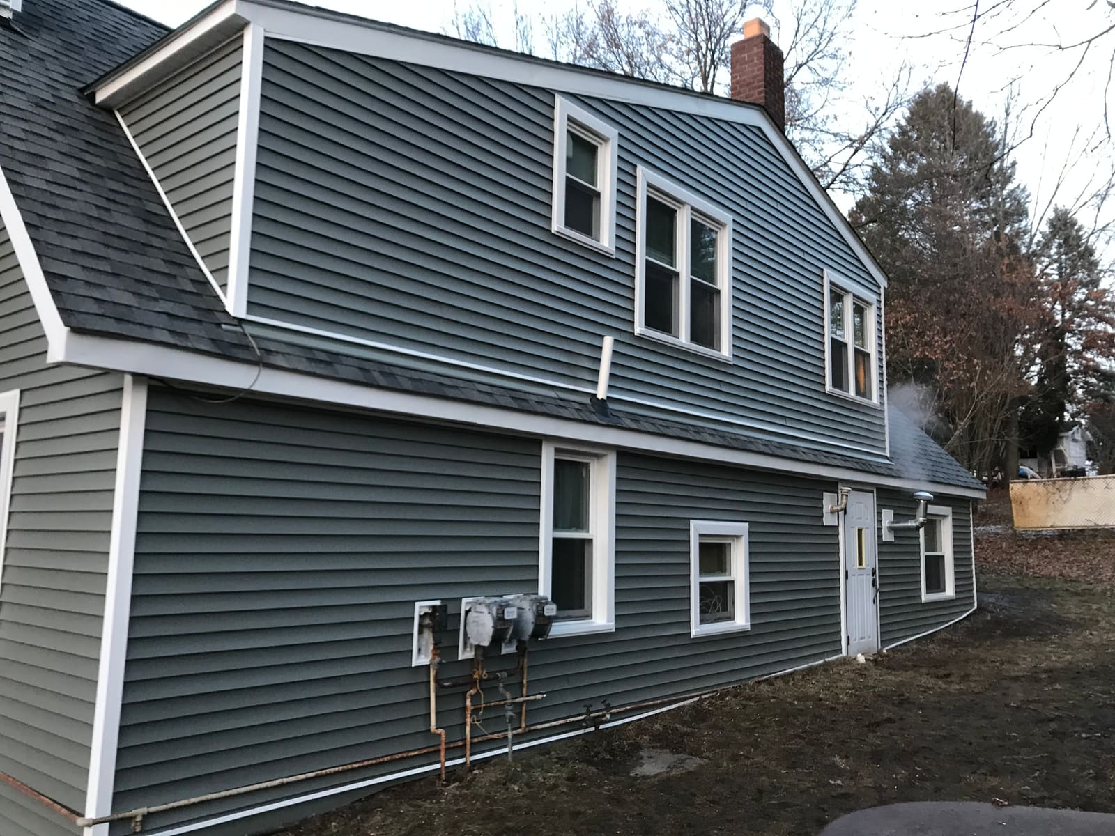 New siding and white window trim on the same side of the Howell home