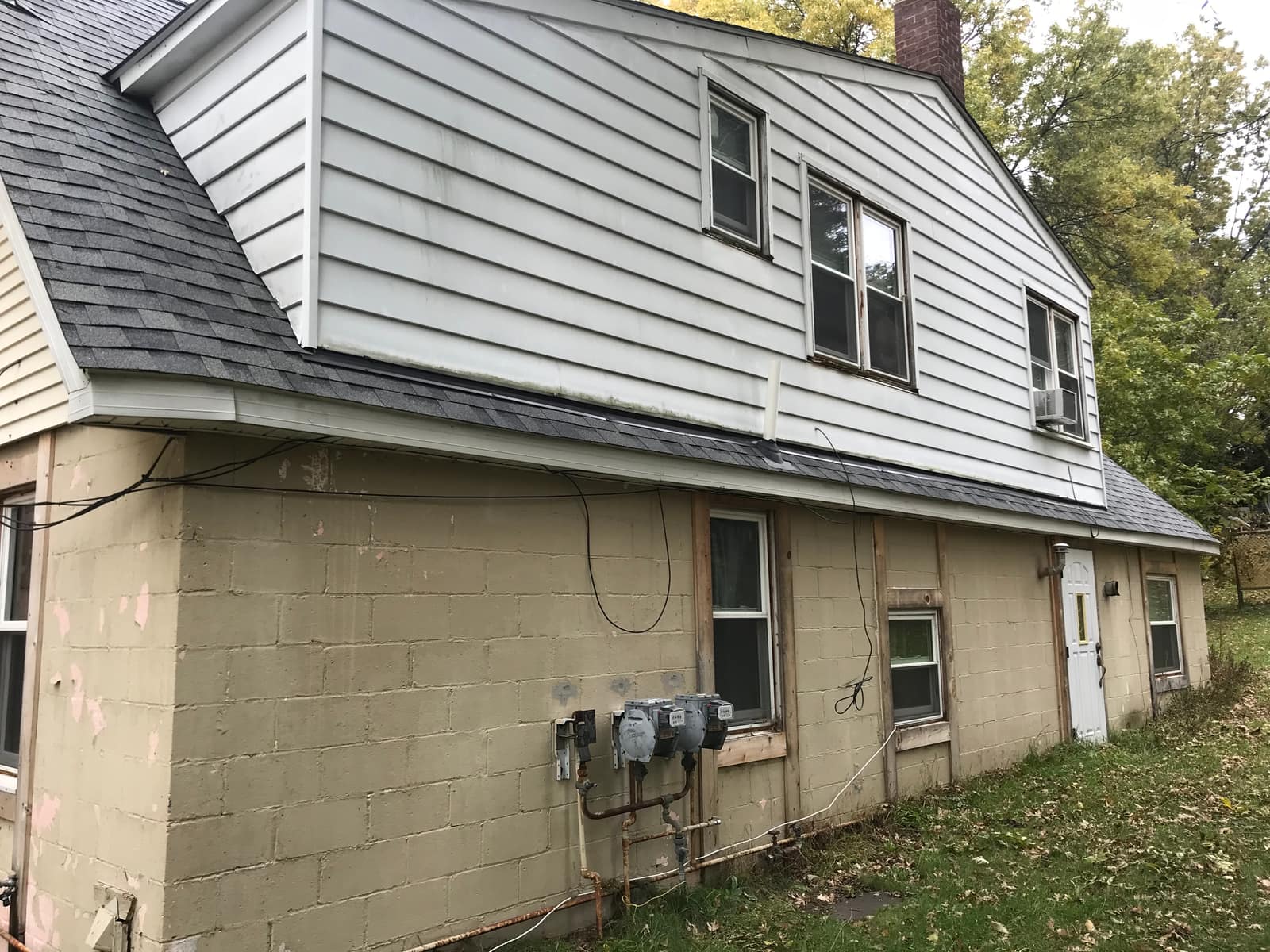Weathered siding and exposed lower wall along the side of the Howell home